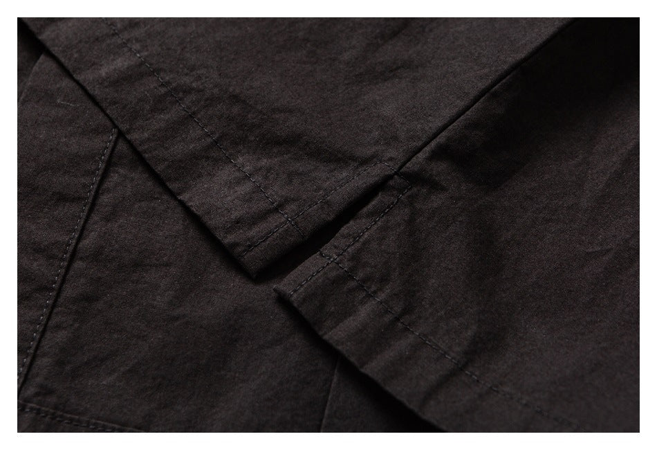 Close-up of dark garment fabric showing overlapping panels and stitched seams.