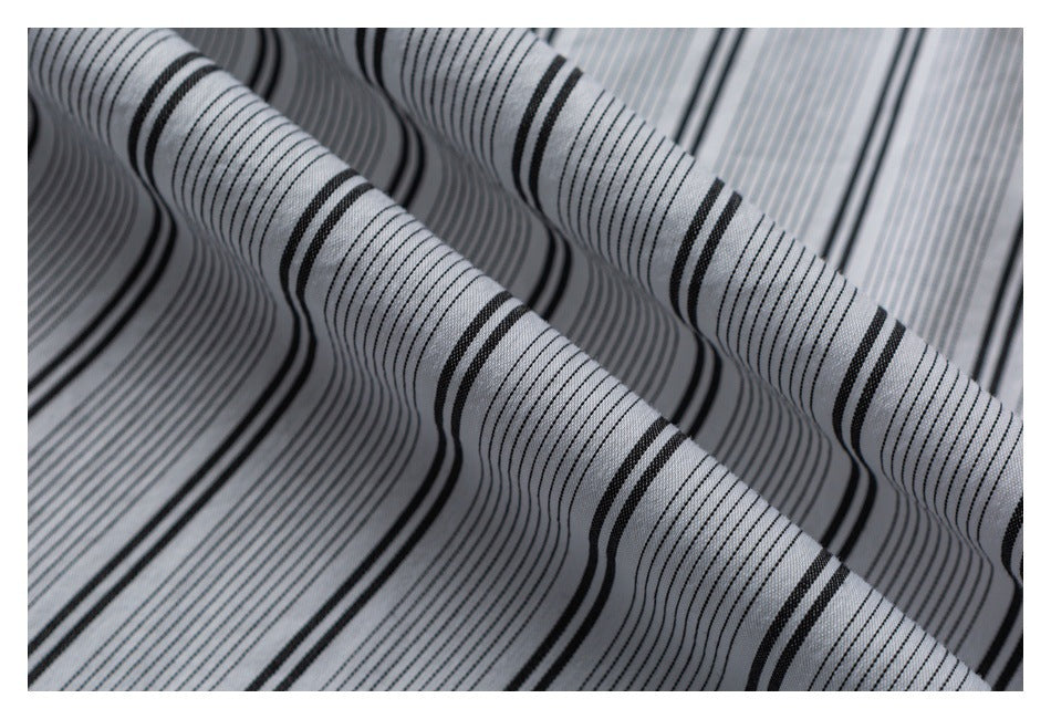 Close-up of folded light gray fabric with fine and bold black stripes.