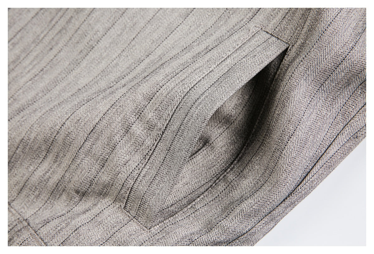 Close-up of a pocket opening in gray-beige patterned fabric, showing the stitched pocket edge.