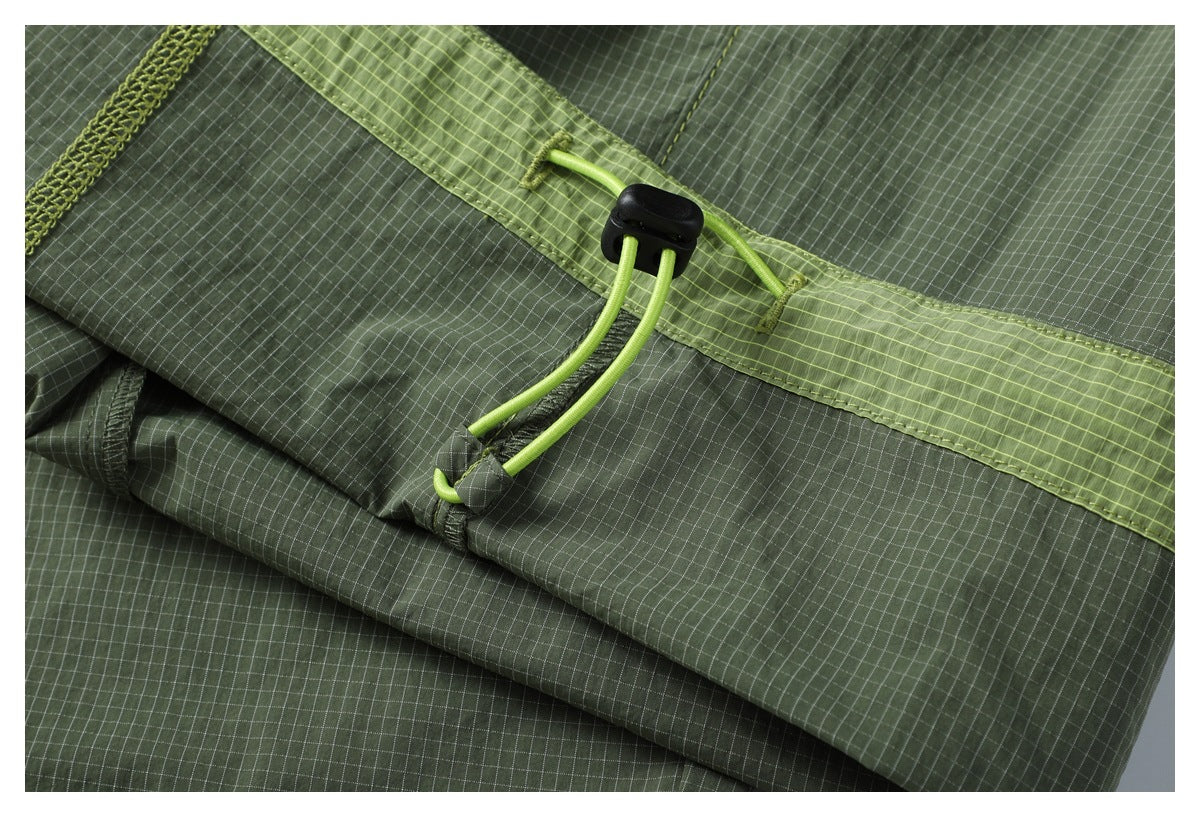 Close-up of a black cord lock and lime drawcord on olive-green grid-patterned fabric.
