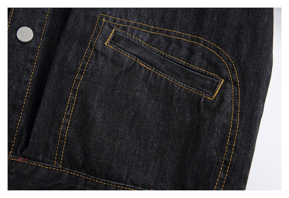 Close-up of a dark denim jacket pocket with a slanted welt opening and gold stitching.
