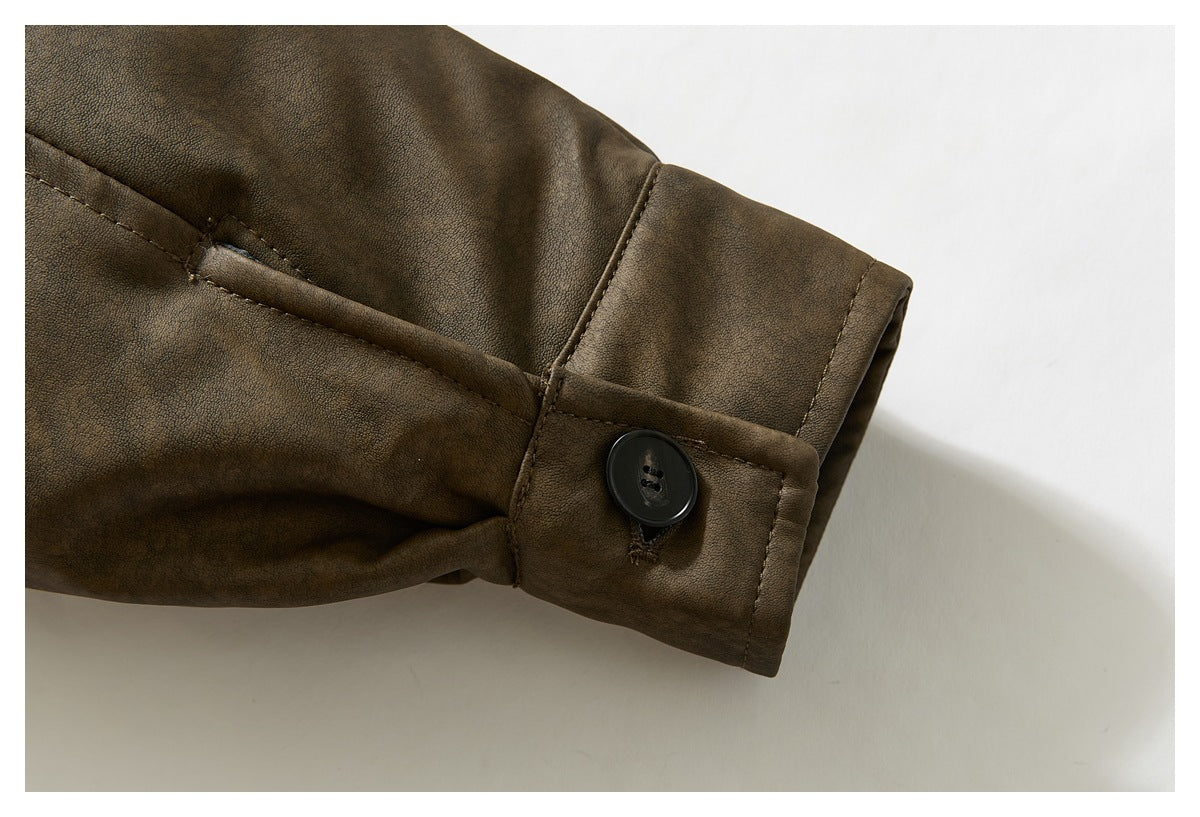 Close-up of a brown jacket sleeve cuff with a black button and stitched button tab.