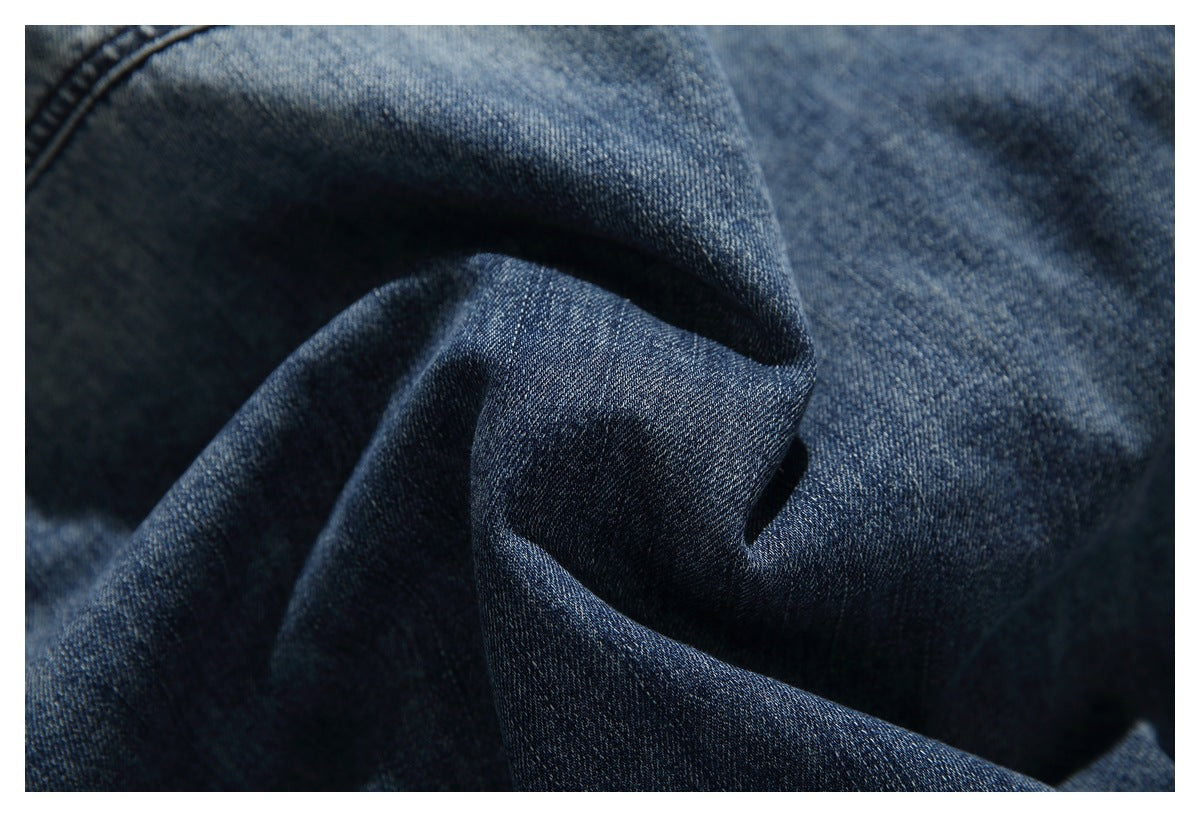 Close-up of dark blue denim fabric gathered into folds, showing its woven texture.