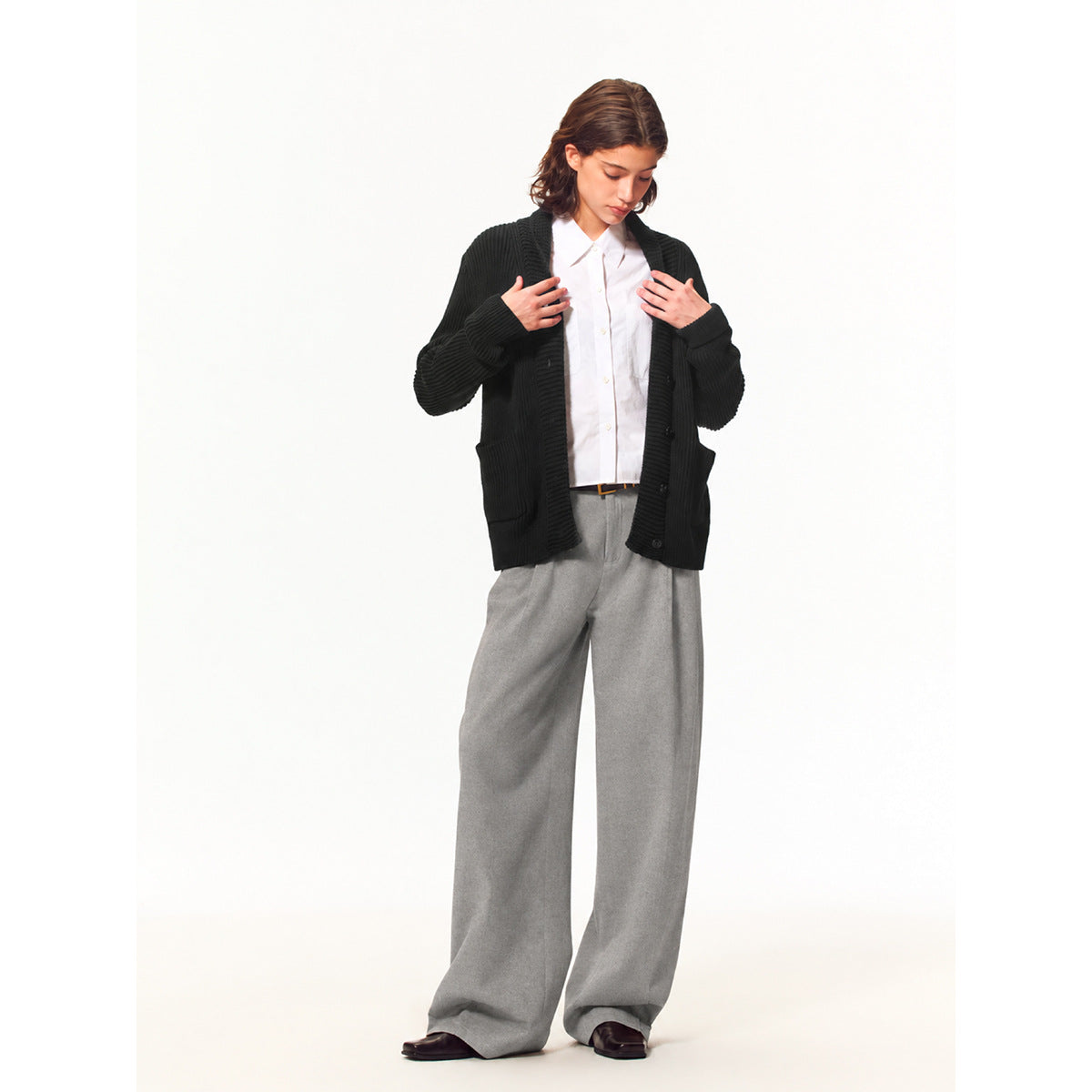 Model wearing a black ribbed button-front cardigan over a white shirt with loose gray wide-leg trousers.
