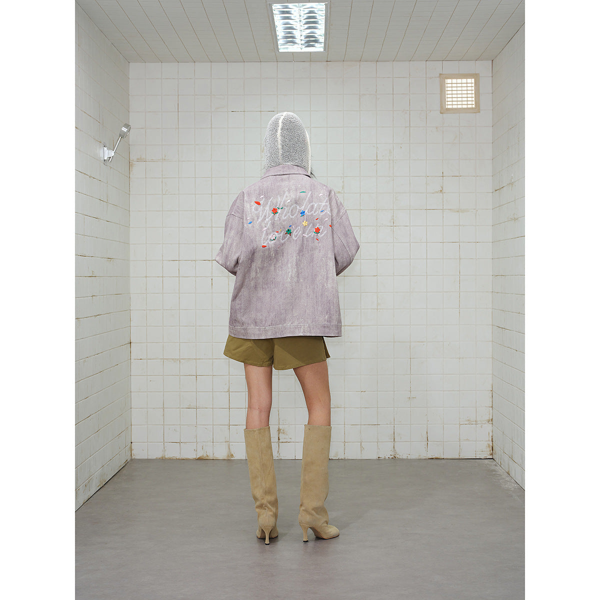 Back view of a model wearing a dusty mauve jacket with colorful floral script embroidery across the back.