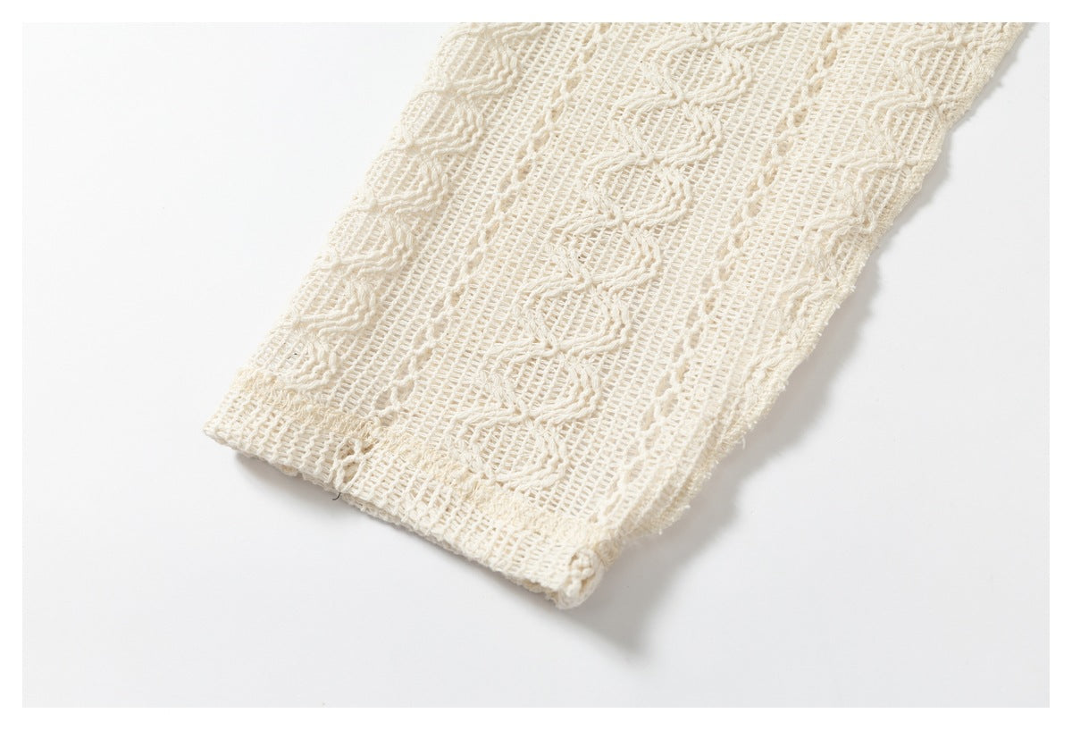 Close-up of the edge of a cream open-knit garment, showing its patterned weave and finished border.