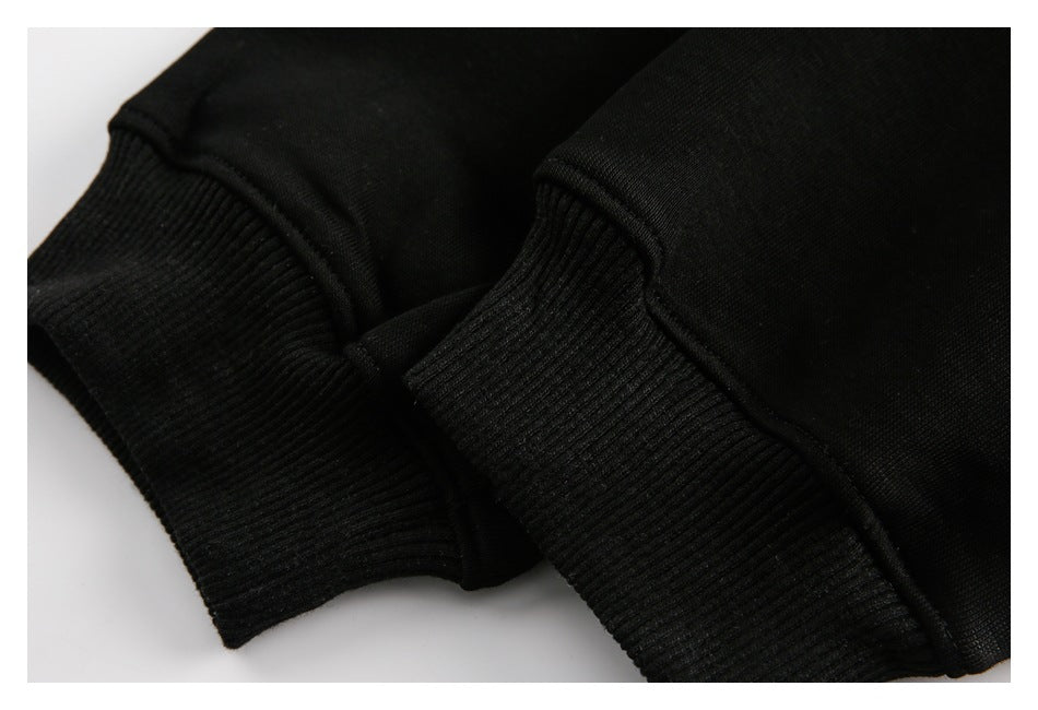 Close-up of two black ribbed cuffs against black garment fabric.