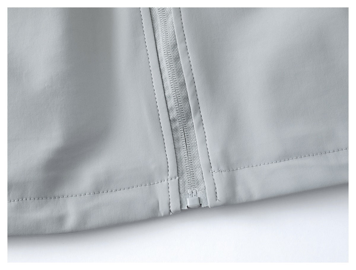 Close-up of the light gray jacket's lower front zipper and hem stitching.