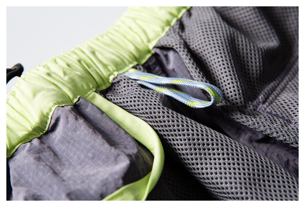 Inside detail of gray shorts with black mesh lining, lime-green waistband, and a looped drawcord.