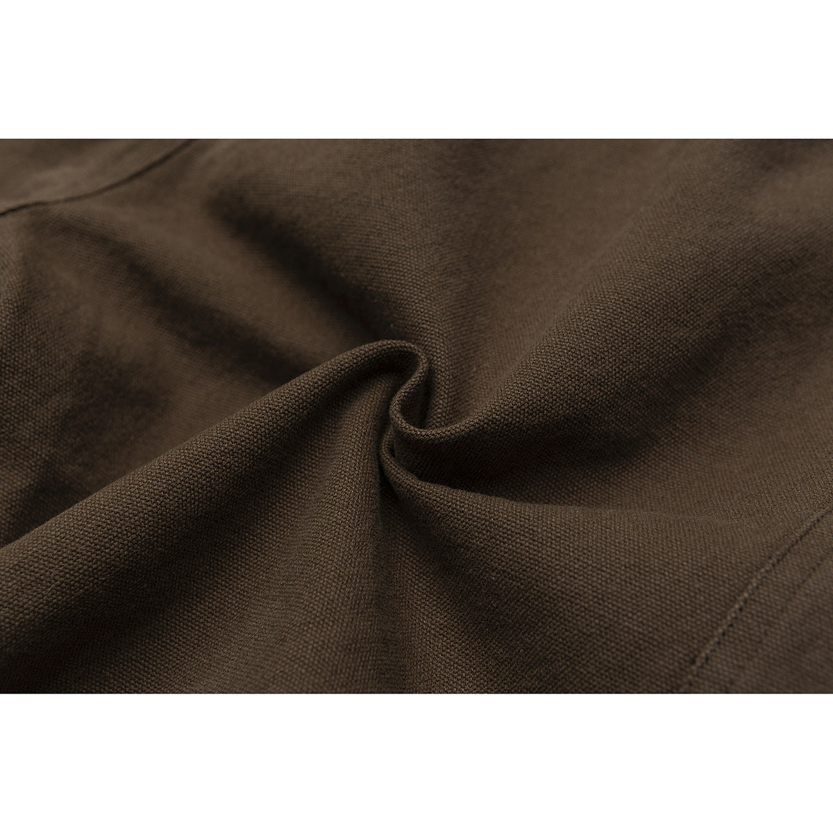 Close-up of the dark brown trousers' textured fabric, draped to show its surface and weave.