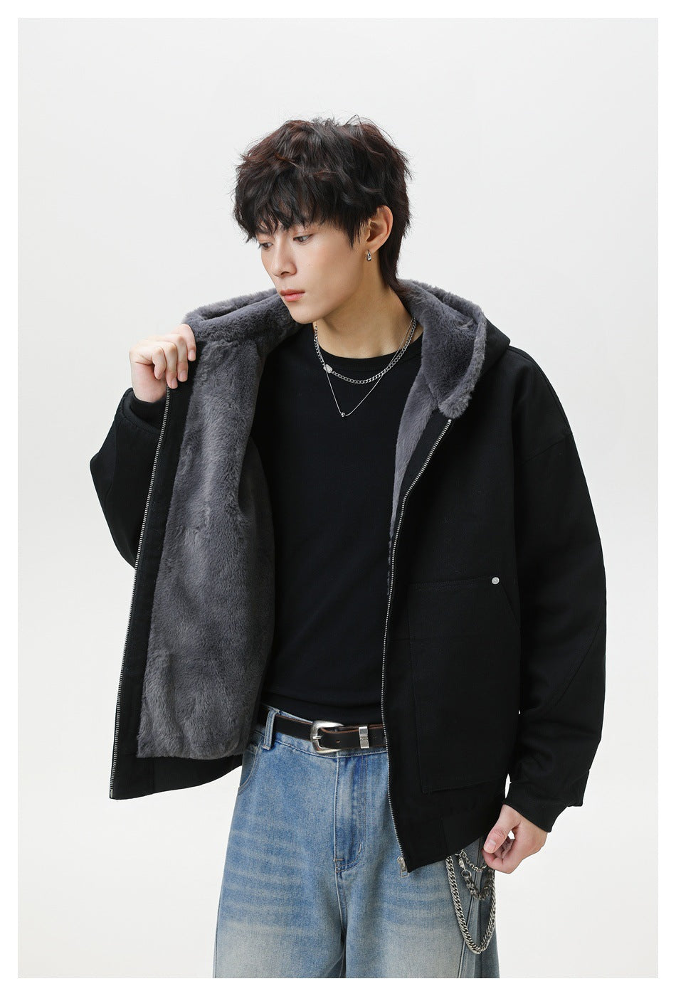 Model displays the open front of a black hooded jacket, showing its gray plush lining and large pockets.