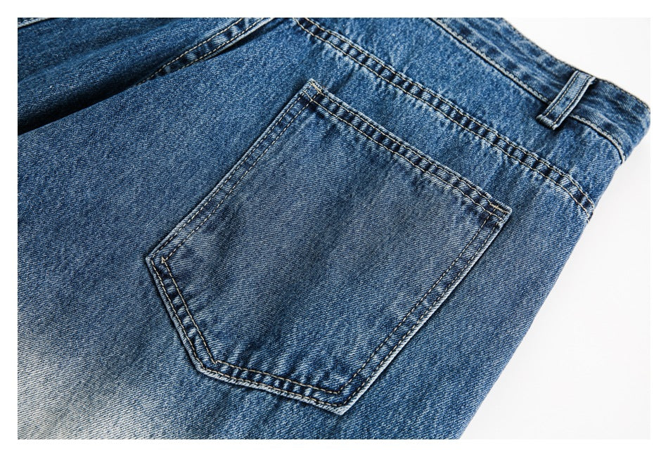 Close-up of a blue denim jeans back pocket with contrast stitching and a belt loop.