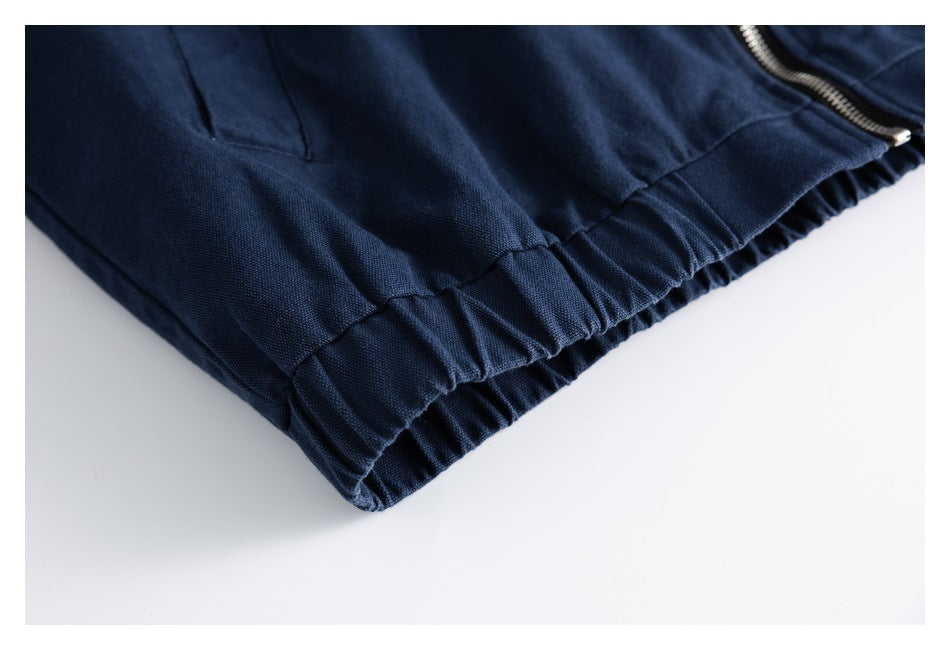 Close-up of a navy jacket's elasticated hem, side seam, and metal zipper.