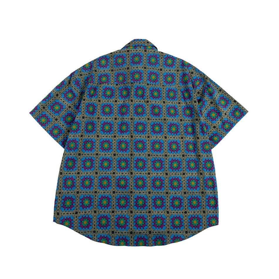 Back view of a gray short-sleeve shirt with a collar and repeating blue, purple, and teal floral squares.
