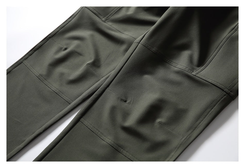 Flat-lay close-up of dark olive pant legs with stitched panels and small slit details.