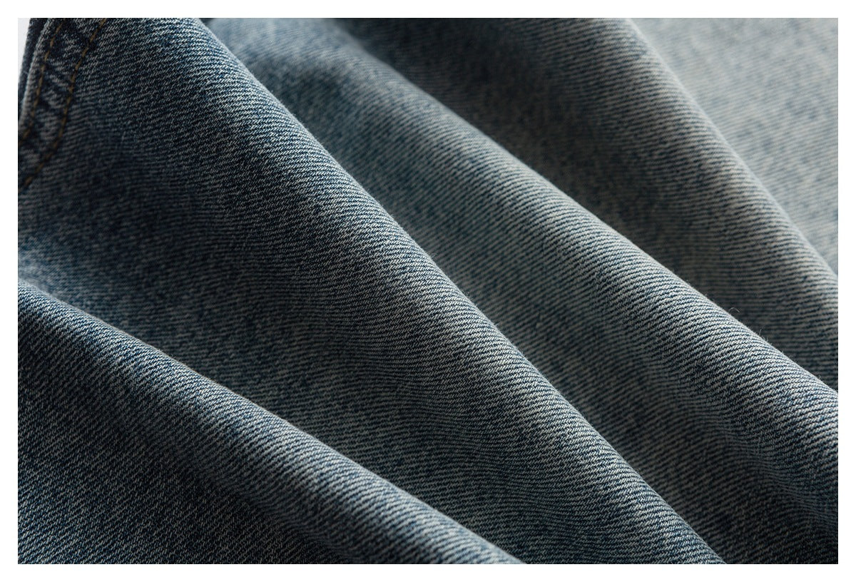 Macro view of dark blue denim arranged in folds, showing its diagonal weave and faded finish.