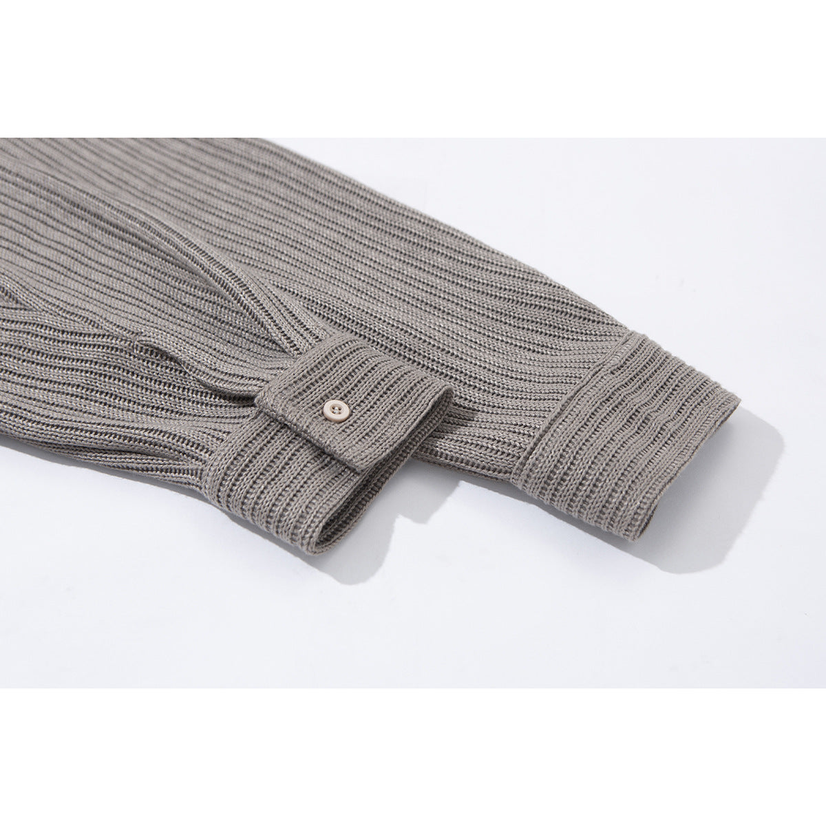 Close-up of a gray rib-knit sleeve cuff with a buttoned tab.