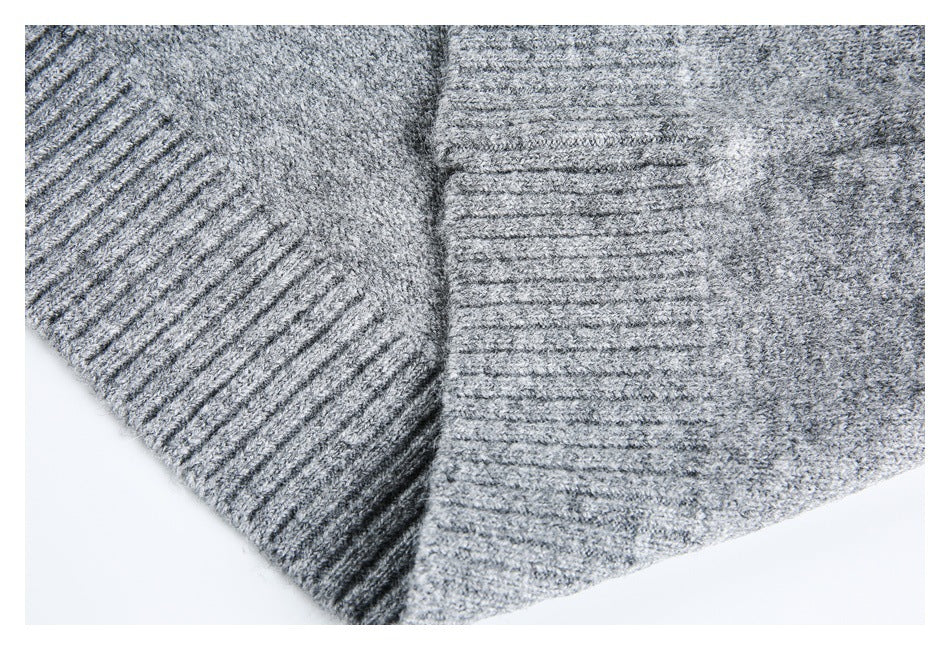 Close-up of a gray marled knit garment showing a ribbed edge and textured knit.