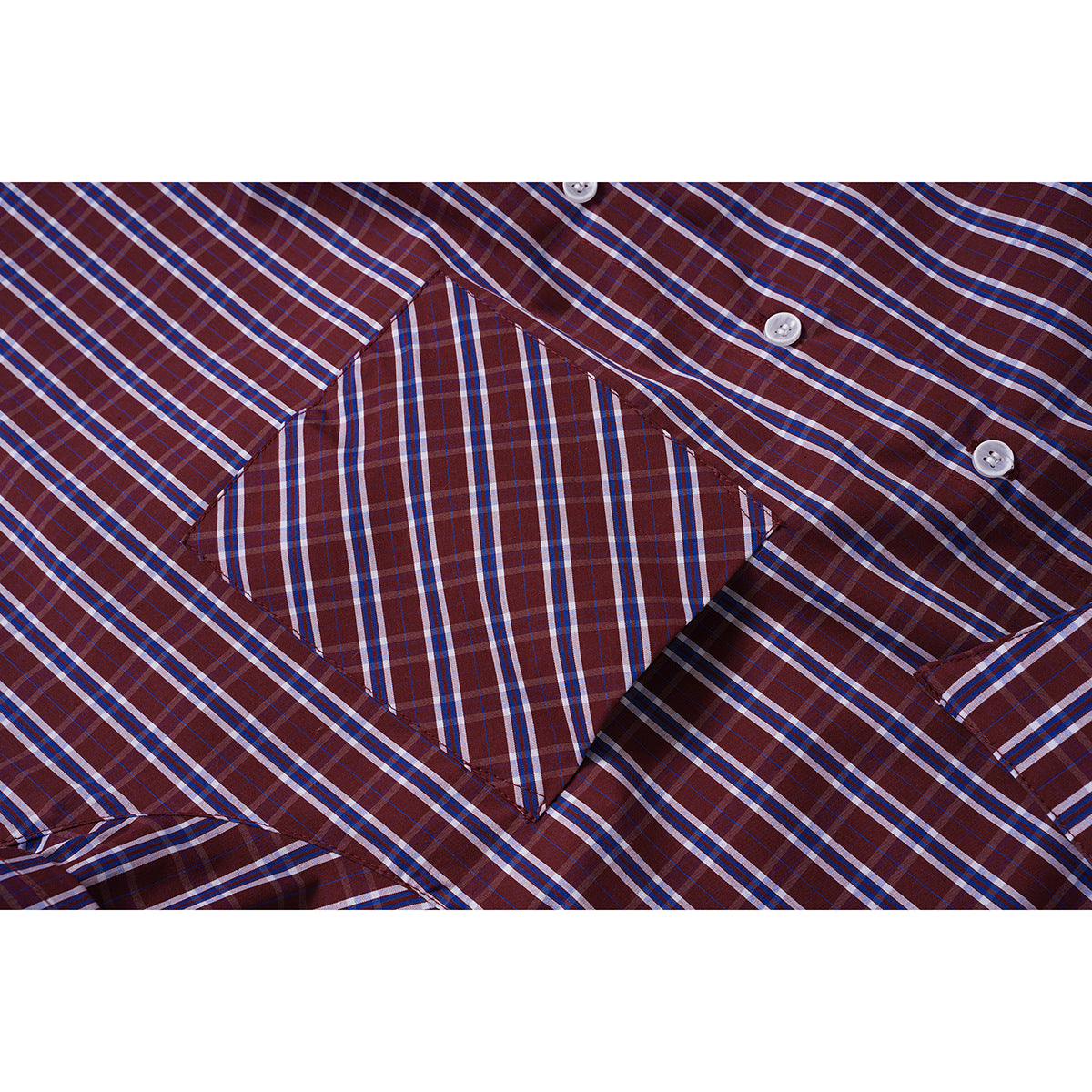 Close-up of the angled chest pocket and white buttons on a burgundy plaid shirt.