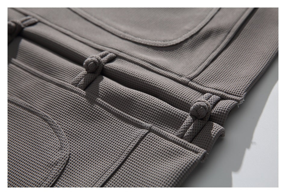 Close-up of the gray jacket's lower edge, textured fabric, pocket stitching, and frog closures.