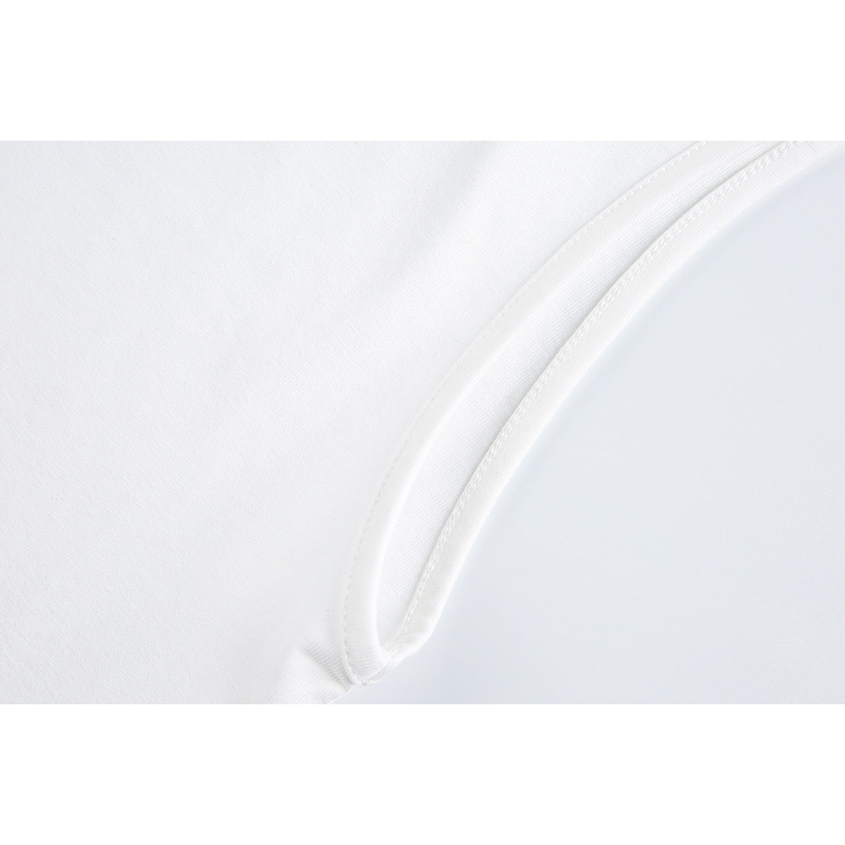 Close-up of white fabric and the curved, stitched edge of a garment opening.