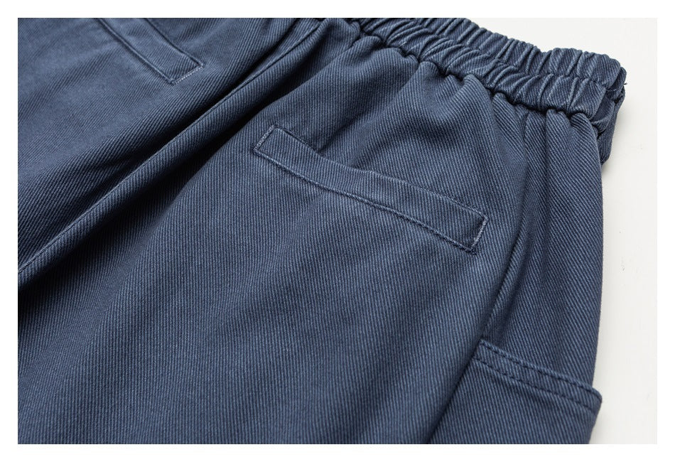 Close-up of blue-gray trousers showing a slanted pocket and stitched side panel.
