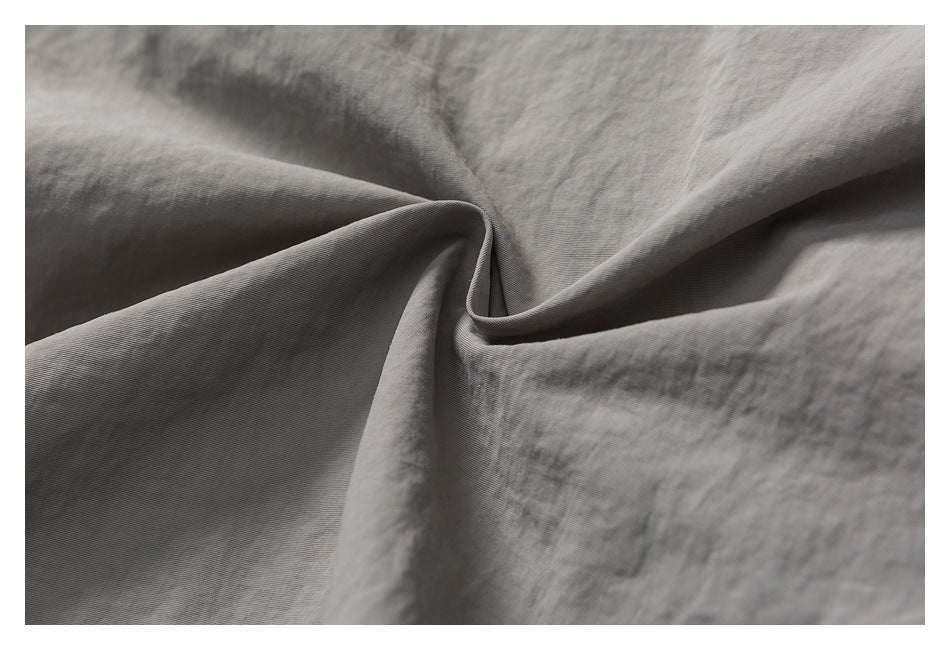 Close-up of gray fabric gathered into soft folds, showing its fine surface texture.