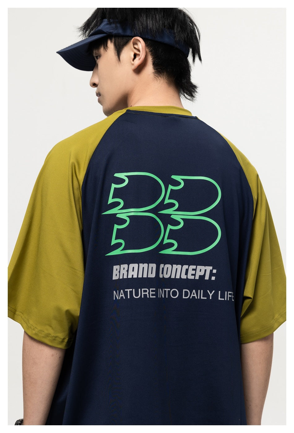 Close-up back view of a navy T-shirt with olive sleeves and a large green-and-white printed graphic.