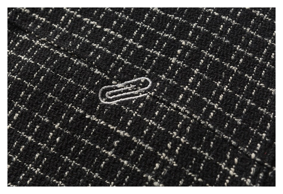 Close-up of black-and-cream patterned fabric with a small white embroidered loop detail.