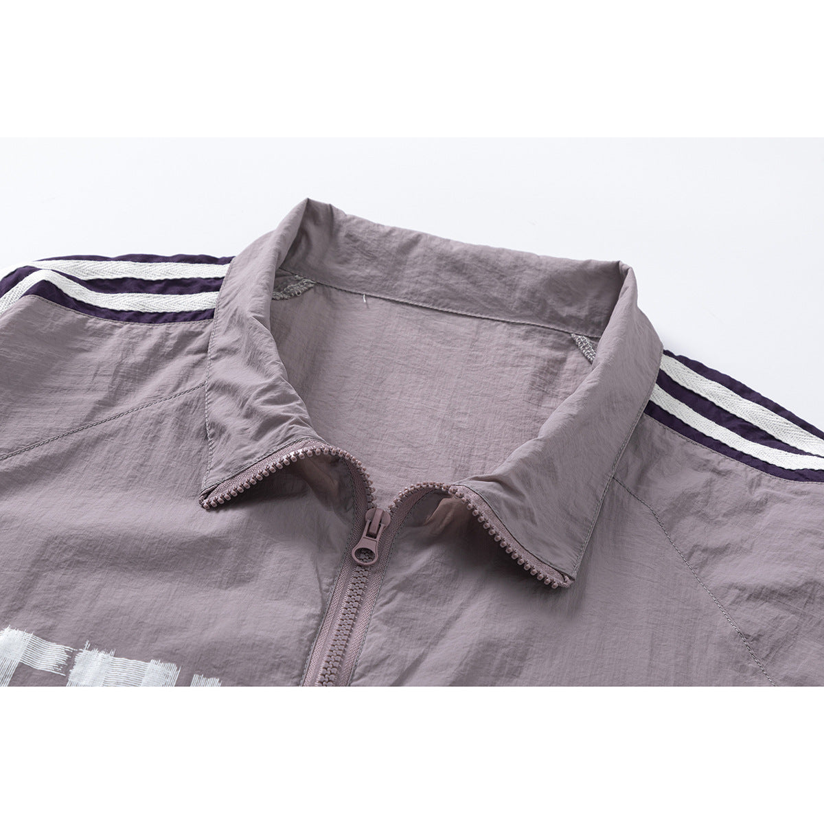 Close-up of a mauve zip jacket collar and zipper, with dark purple and white shoulder stripes.