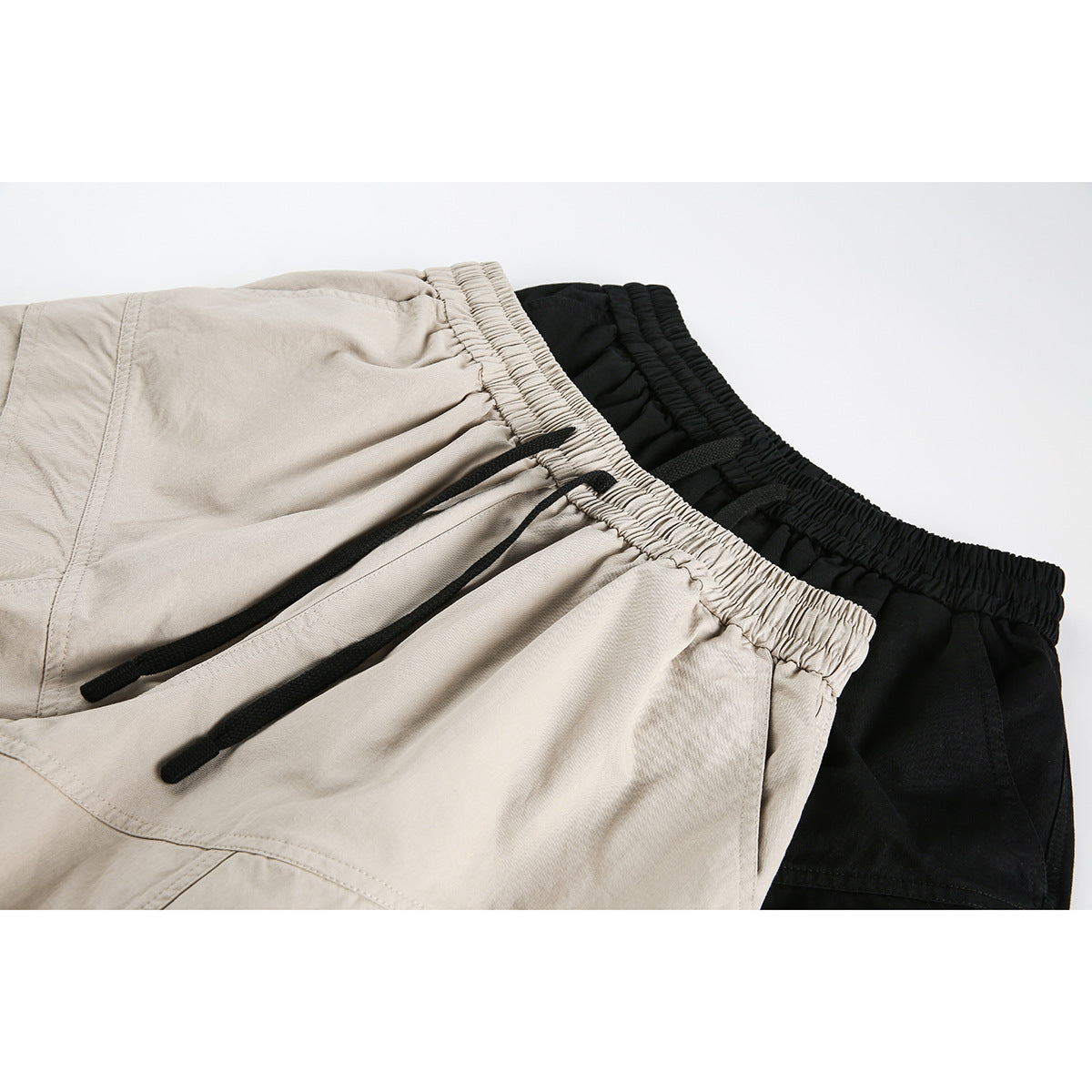 Close-up of beige and black shorts showing elastic waistbands and black drawstrings.