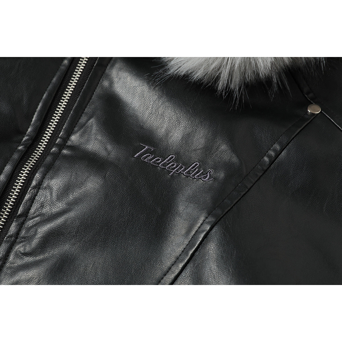 Close-up of stitched lettering on the black jacket beside its zipper and a metal snap.