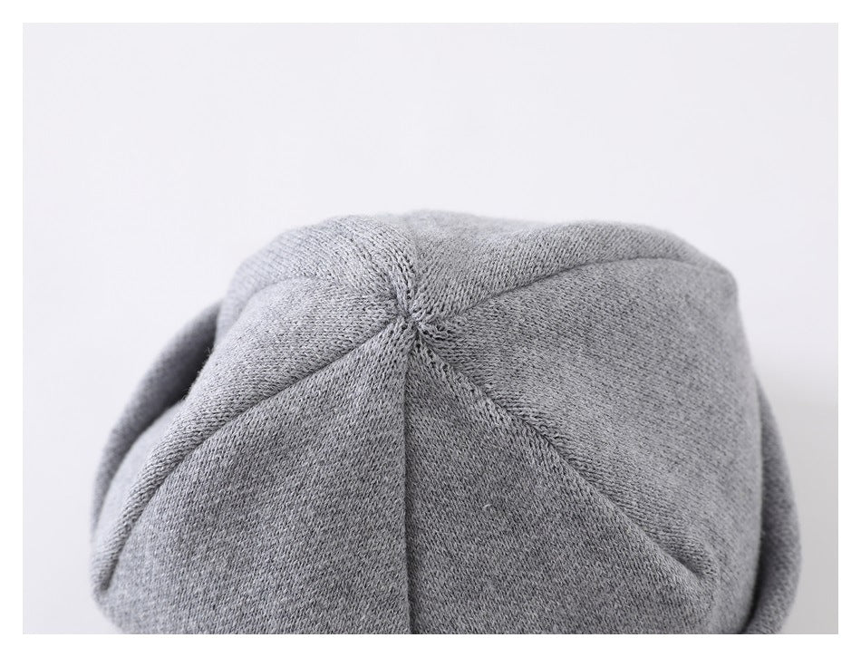 Close-up of the light gray knitted cap crown, where several stitched panels meet.