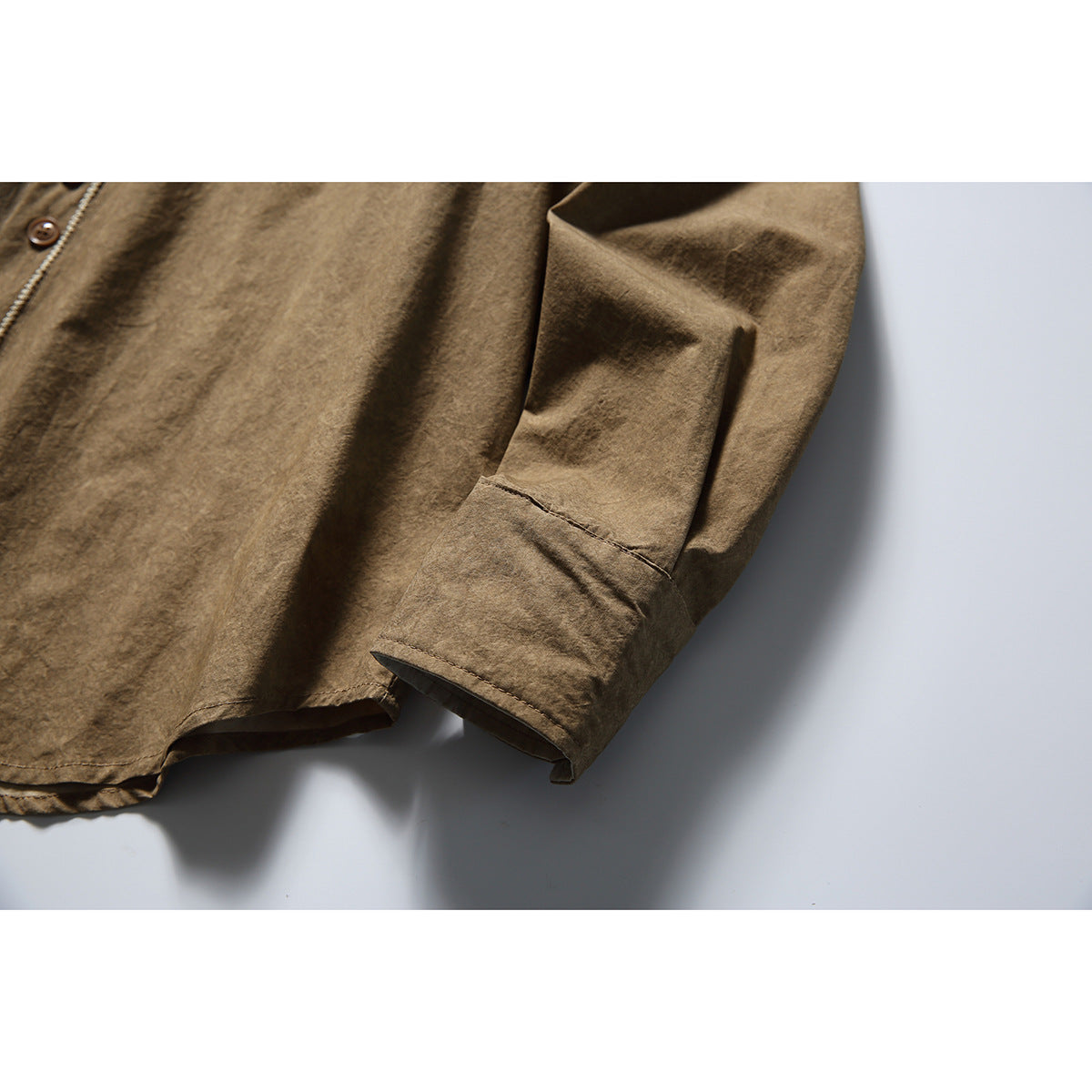 Close-up of the brown shirt's long sleeve, showing the cuff and stitching.