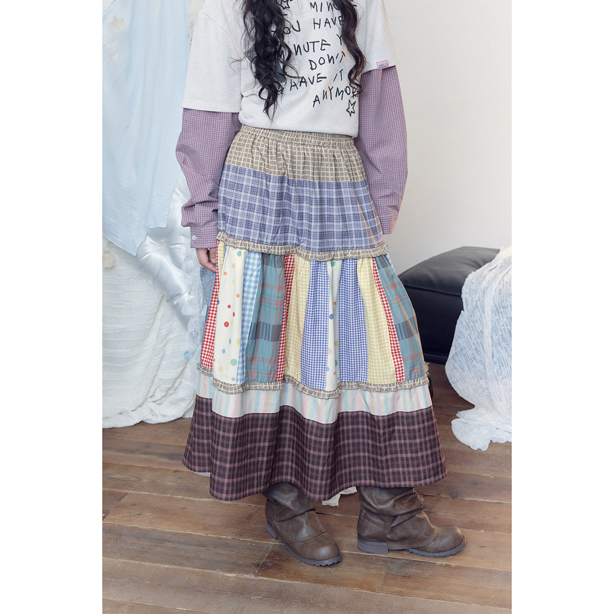 Close view of a model wearing a long tiered skirt with colorful patchwork panels, elastic waist, and ruffled seams.
