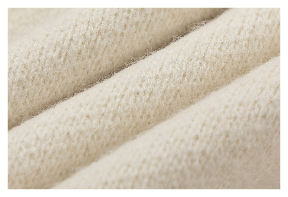 Macro view of the cream sweater's fuzzy, textured knit stitches.