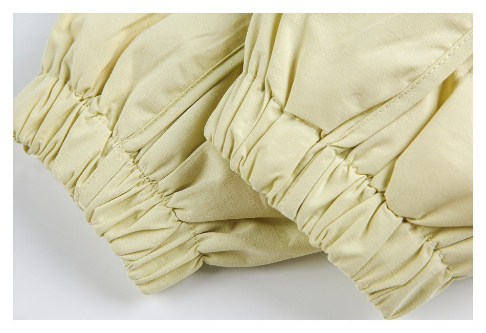 Close-up of gathered elastic cuffs on pale yellow garment fabric.