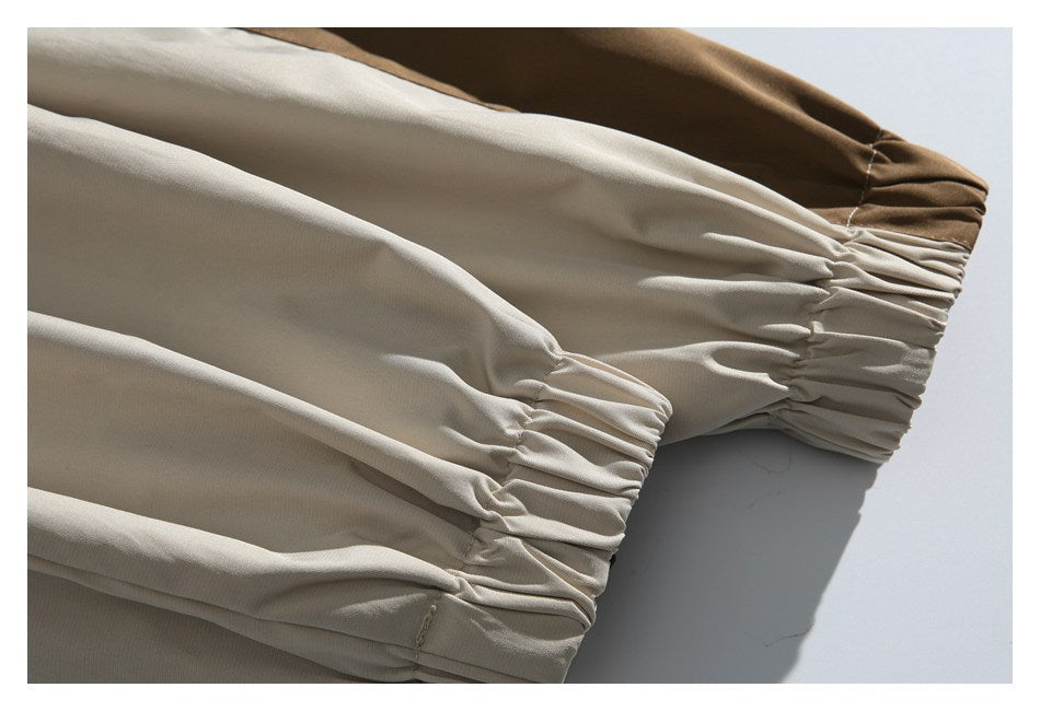 Close-up of gathered elastic cuffs on the beige jacket, with a brown contrast panel at one cuff.