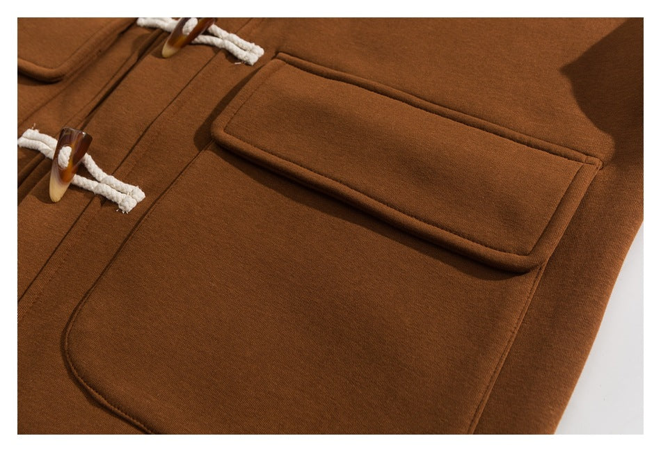Close-up of a brown garment's large stitched pocket and toggle closures.
