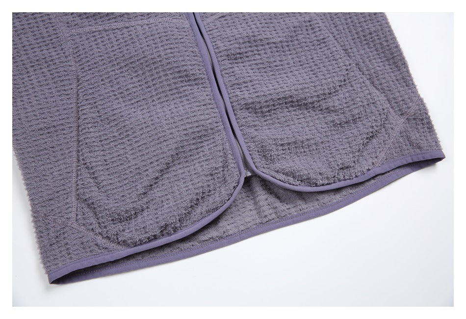 Close-up of the gray garment's lower front, showing two patch pockets and purple-gray edge binding.
