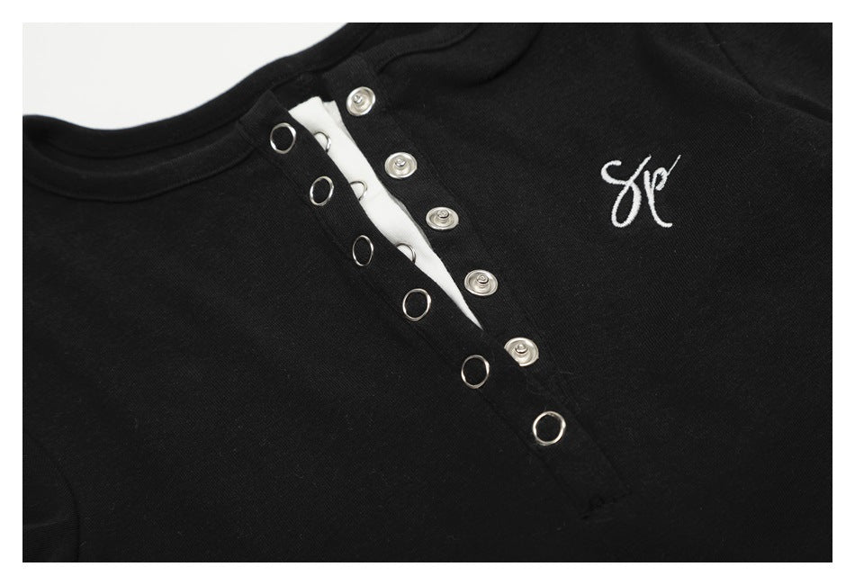 Close-up of the black top's metal snap placket and small white script embroidery on the chest.