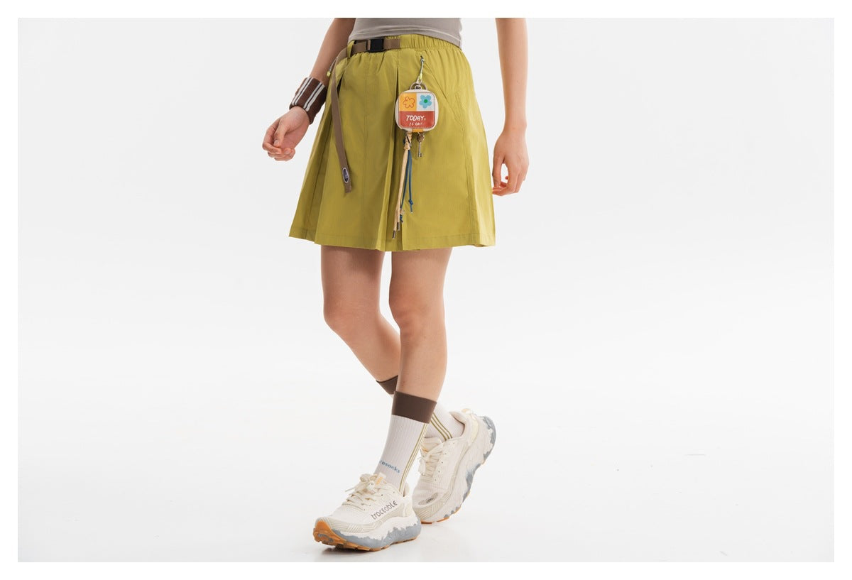Cropped view of a yellow-green skirt with a belt, hanging accessories, and pleated panels.