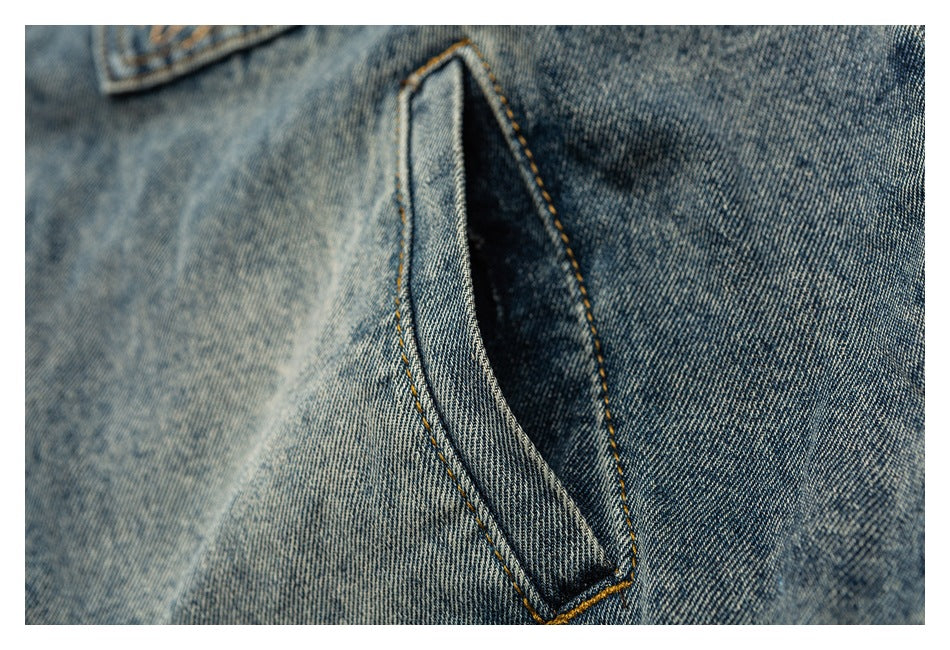 Close-up of a blue denim pocket opening with contrasting golden stitching.