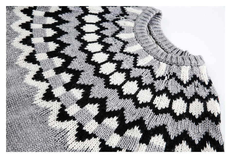 Close-up of the sweater's upper front, showing a gray, black, and cream geometric knit pattern and ribbed neckline.