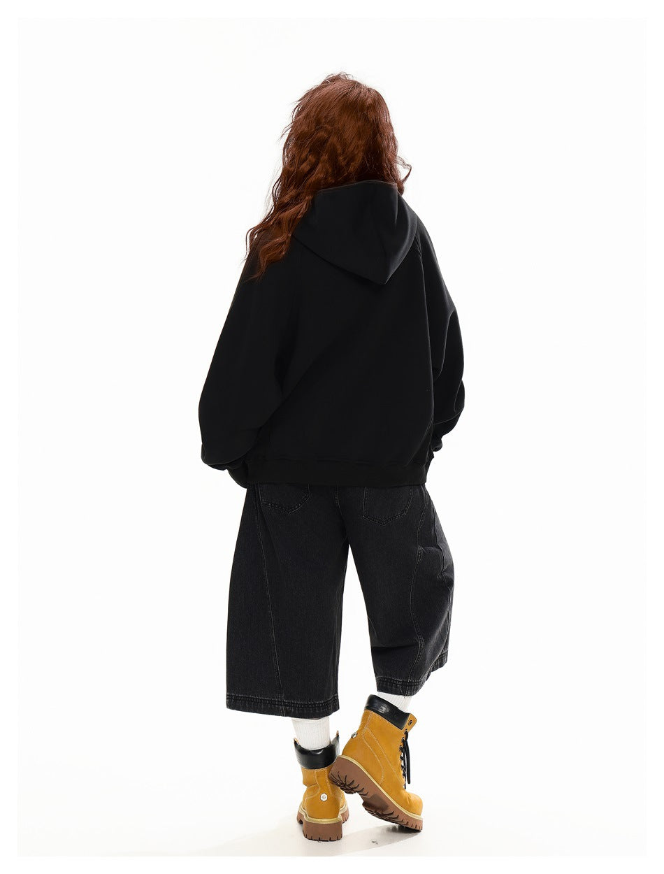 Rear view of a model wearing a black hooded sweatshirt with dark cropped wide-leg jeans and tan boots.