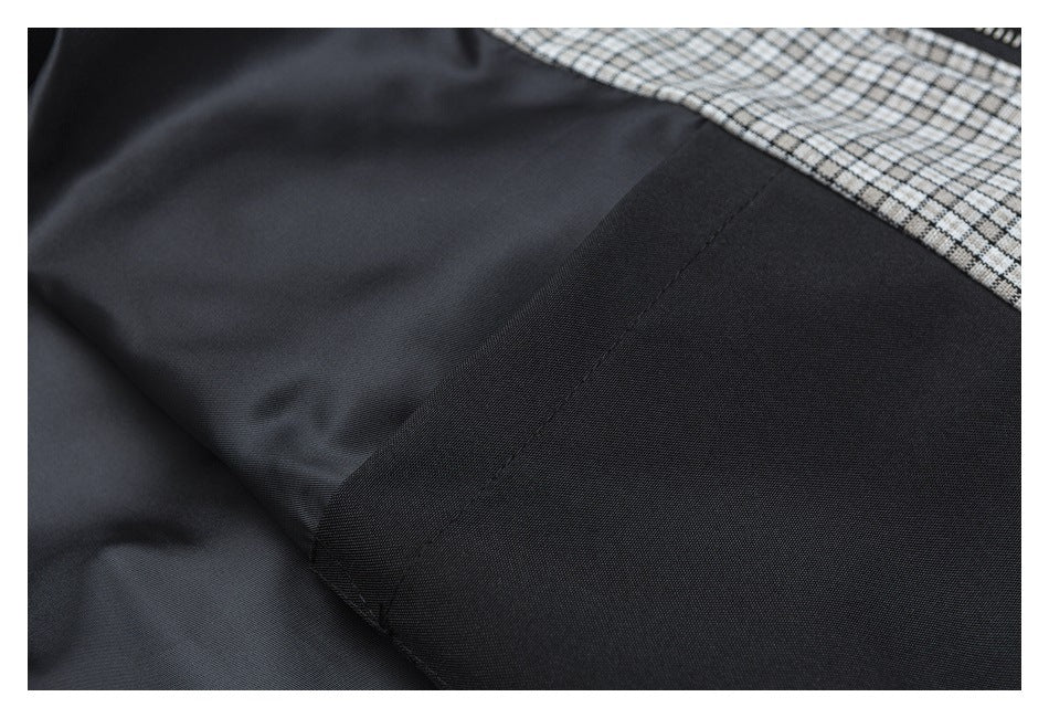 Close-up of black garment fabric and seam beside a gray checked panel.