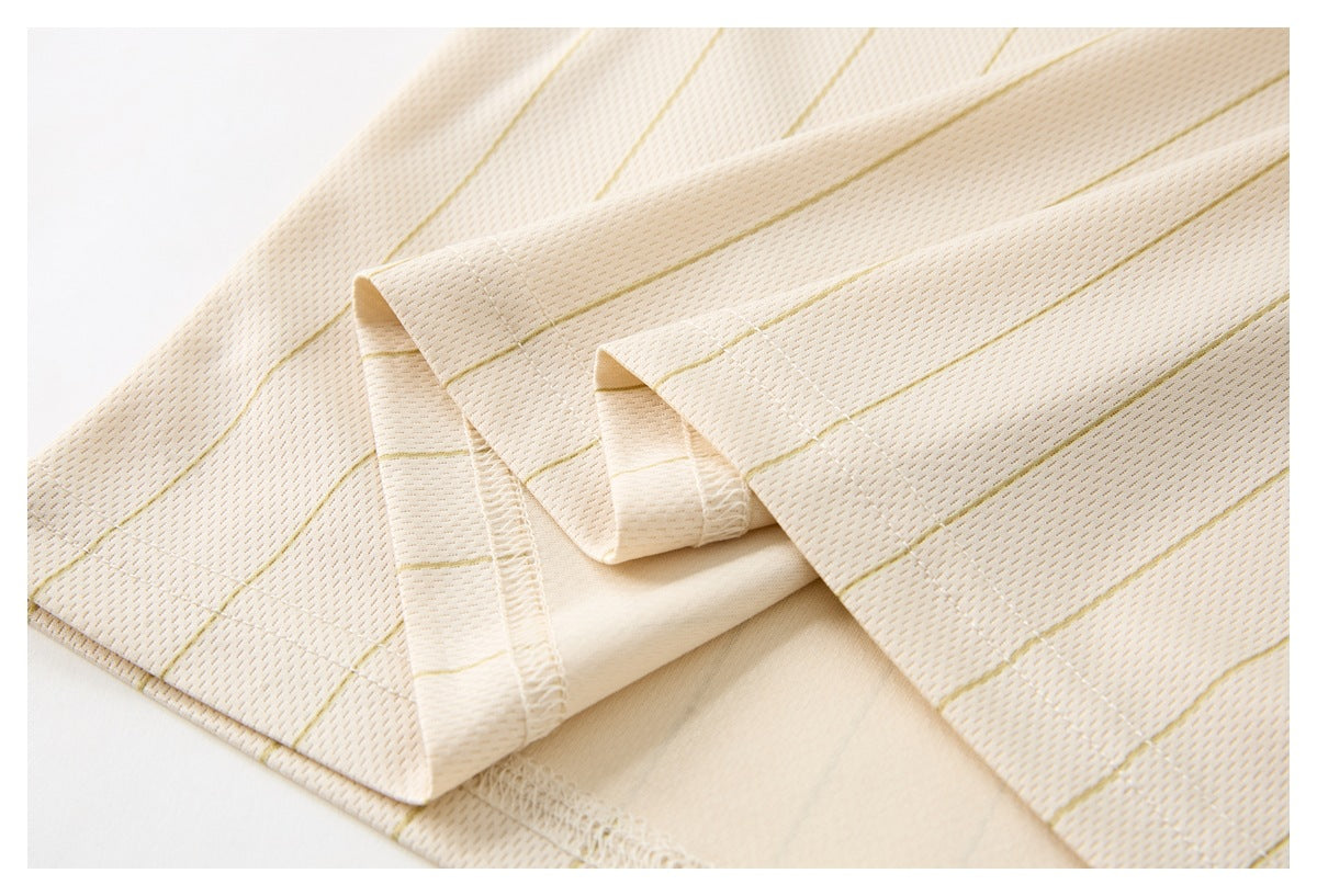 Close-up of cream fabric with fine gold pinstripes, showing a folded, stitched seam.