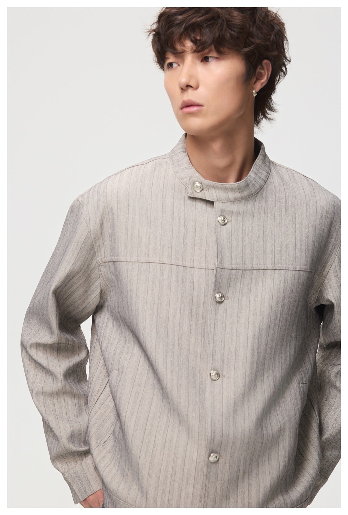 Close-up of a model wearing a light gray pinstriped jacket with a stand collar and silver buttons.