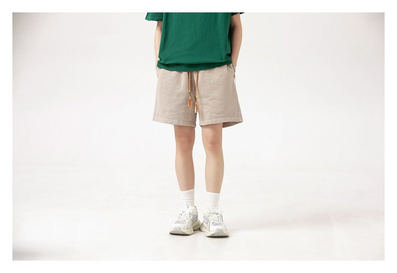 Front view of a model wearing light beige drawstring shorts with a green T-shirt.