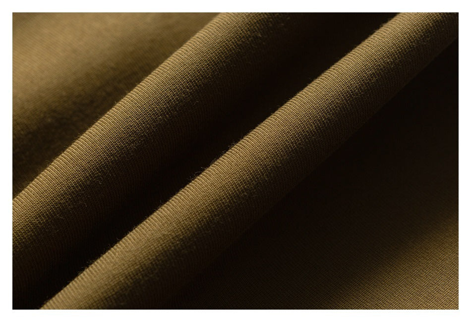 Close-up of olive-brown knit fabric folded into diagonal ridges, showing its fine textured weave.